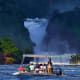Murchison Falls in Uganda with tourists in a boat on the Nile River below the cascading waterfall and forested canyon walls